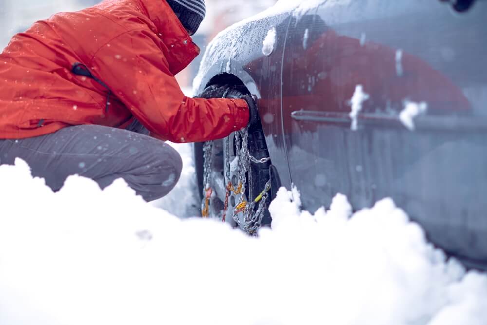 Man plaatst sneeuwketting op reserveband