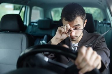 Man zit vermoeid achter het stuur van zijn auto